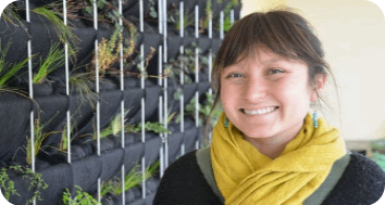 Persona sonriendo con huerto vertical a la izquierda.